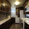 This design maximizes storage in a galley kitchen using standard upper cabinets to create a shallow pantry on one side.