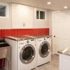 A beautiful, functional laundry room takes over previously unfinished basement space.  A splash of red tile adds punch to the white and stainless steel aesthetic.  The industrial sink and faucet makes messy clean-ups a breeze.